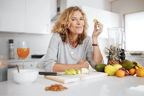 Erwachsene Frau in der Küche mit Obst und Gemüse für eine gesunde Haut